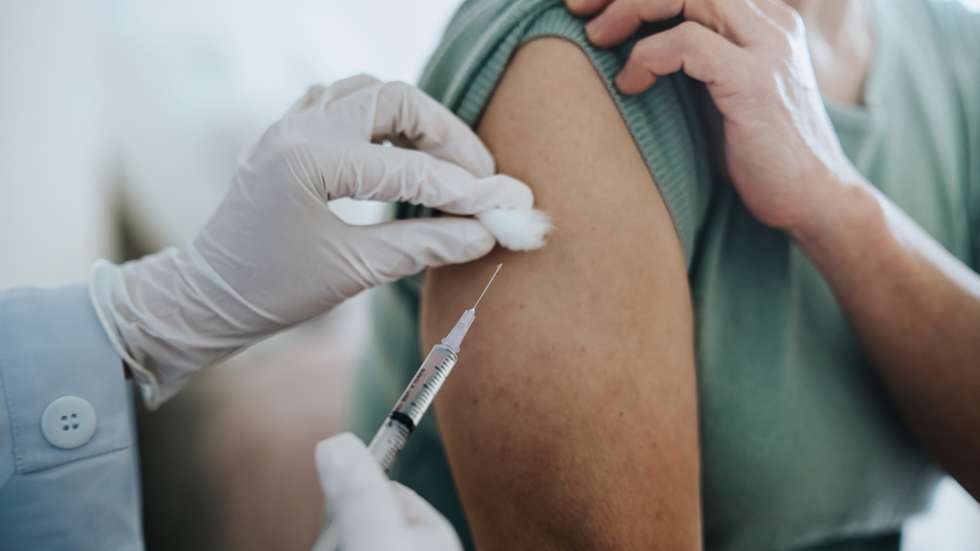 Close up of senior Asian woman getting Covid-19 vaccine in arm for Coronavirus immunization by a doctor at hospital. Elderly healthcare and illness prevention concept