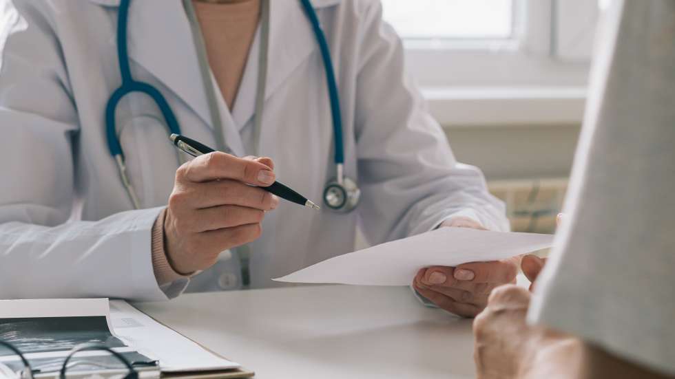 Unrecognizable doctor consulting patient. Giving piece of paper with instructions and recommendations