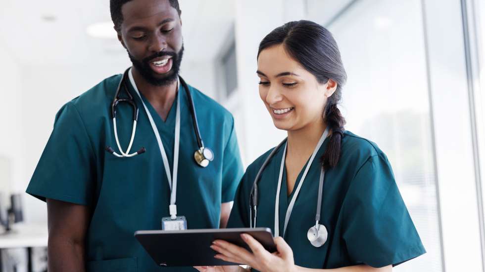 Two doctors looking at digital tablet in hospital hallway