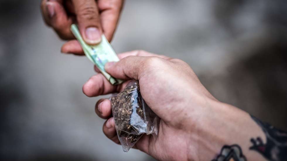 An addict with money buys a dose from a dealer on the street. Addiction concept.