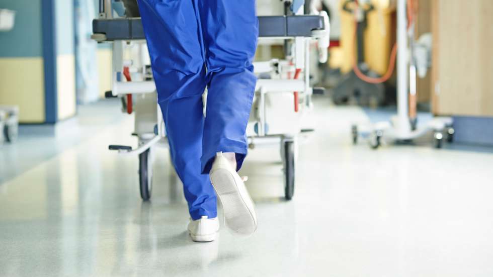 Legs of medic running with gurney along hospital corridor