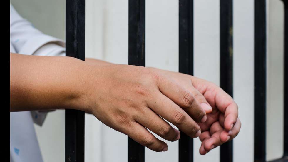 Cropped Hands Of Woman On Security Bar In Prison