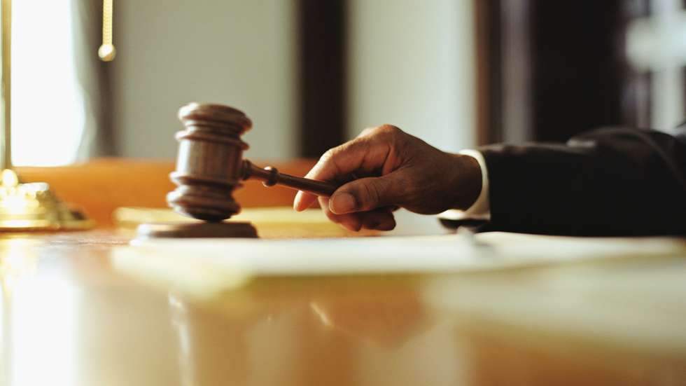 Male judge striking gavel in courtroom, close-up