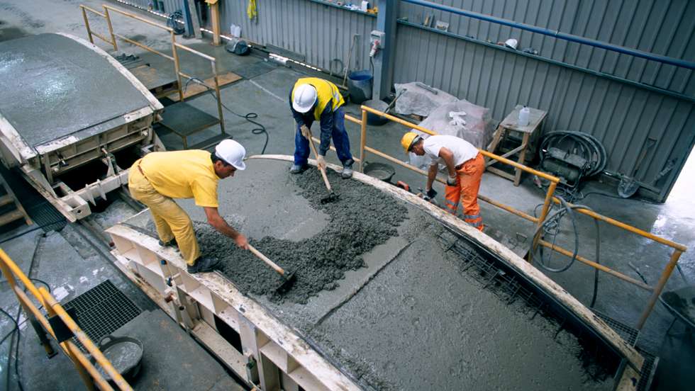 Hand finishing and surface trowelling for a concrete tunnel lining segment in a steel mould before steam curing. Spanish High Speed Rail project, on site factory.