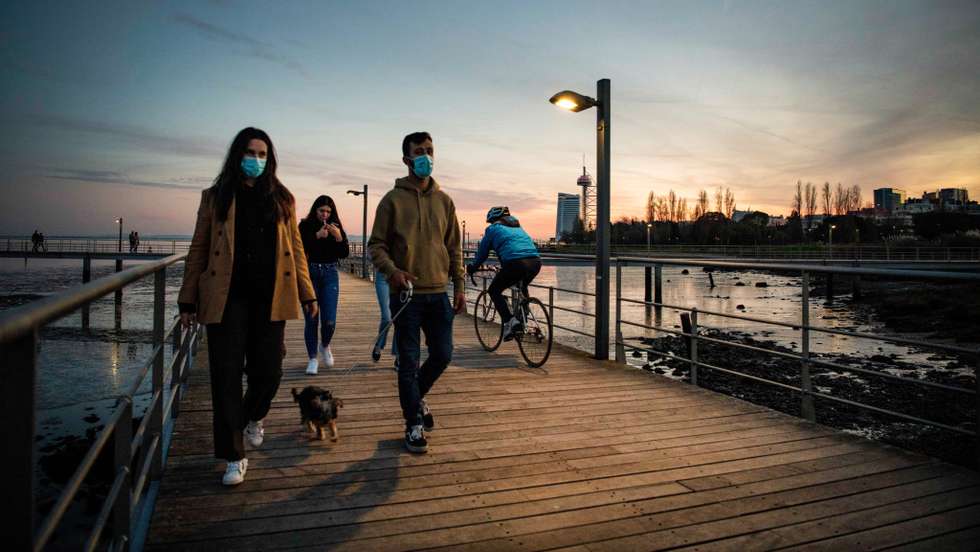 People wearing face masks are seen walking along the Tagus