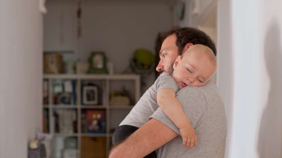 Dad putting to sleep baby boy in his arms