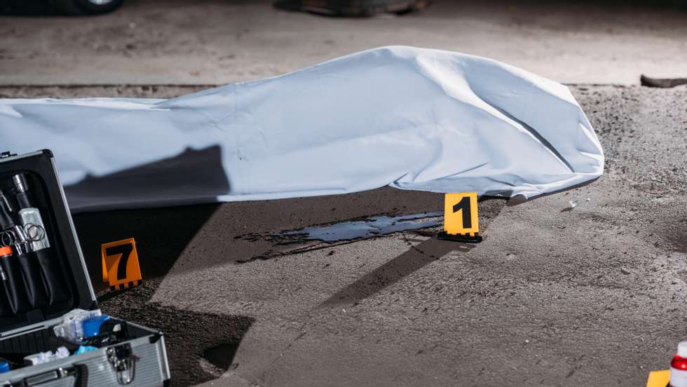 close up view of corpse in body bag and case with investigation tools at crime scene