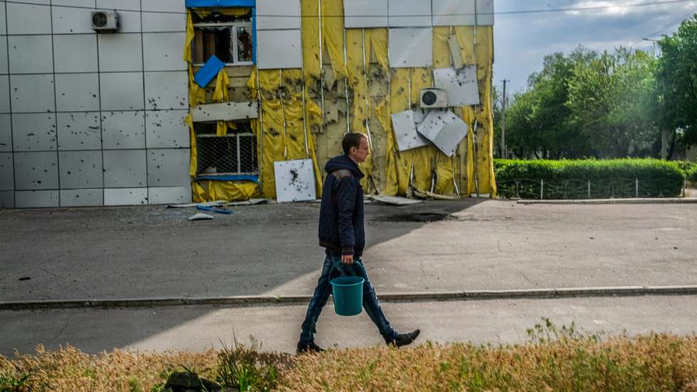A man carries two buckets of water to his house while the