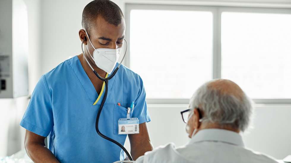 Nurse examining patient in clinic during COVID-19