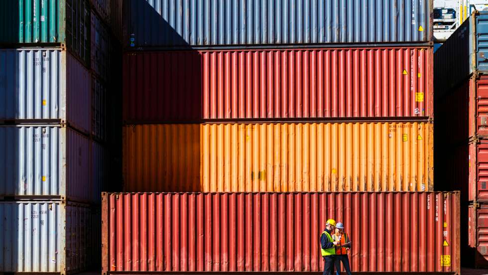Workers having discussion against cargo containers