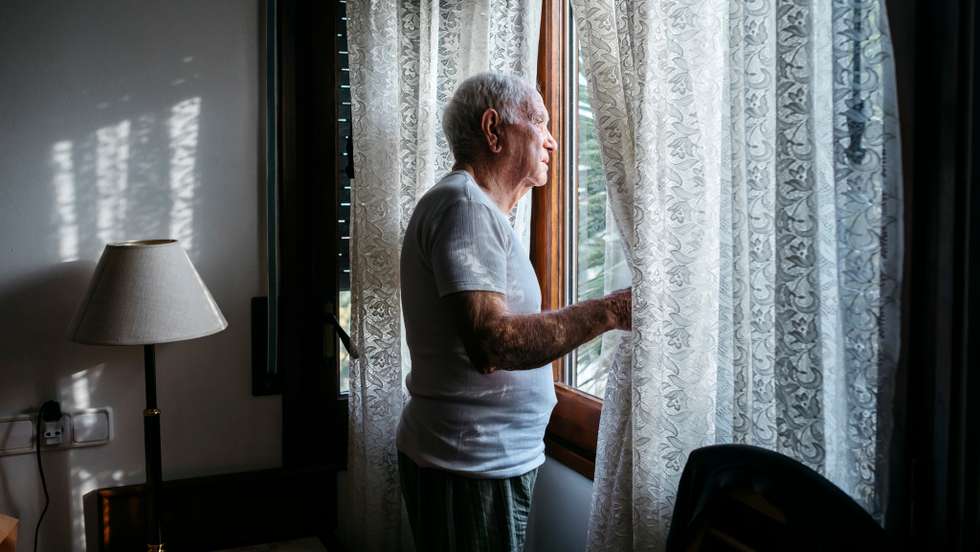 Man looking through window at home