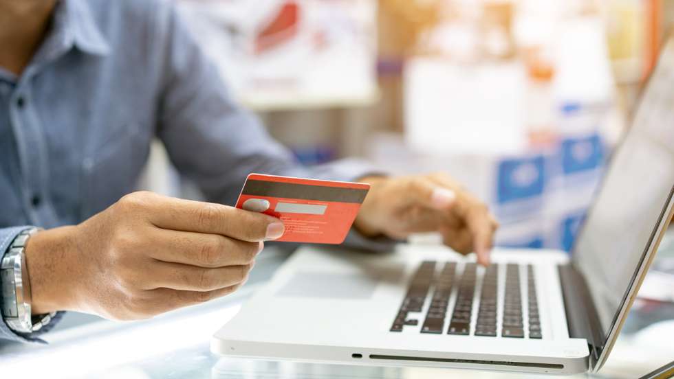 Hands holding credit card, typing on the keyboard of laptop, onine shopping detail close up