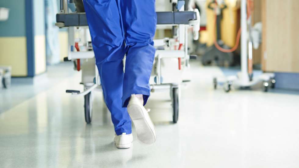 Legs of medic running with gurney along hospital corridor