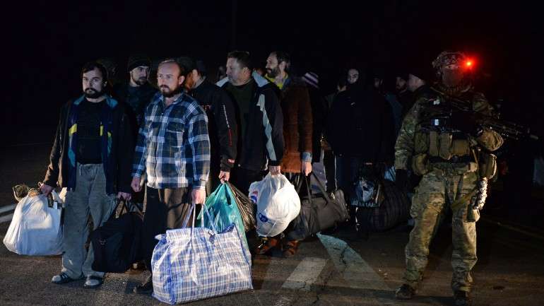 Prisioneiros esperavam pela troca, vigiados por soldados armados