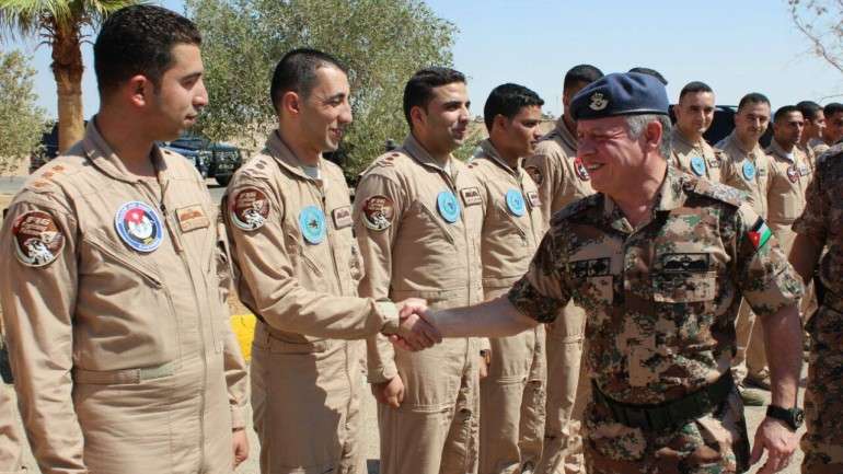 Muaz Kasasbeh, à esquerda na imagem, numa cerimónia de cumprimentos com o rei da Jordânia