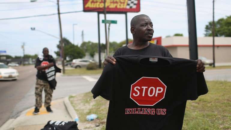 Eric Quattlebaum vende uma t-shirt onde se lê "parem de matar-nos", depois da morte de Walter Scott, em South Carolina