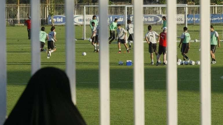 Em 2006, uma iraniana assiste ao treino da seleção, estando impedida de entrar no estádio para ver o jogo