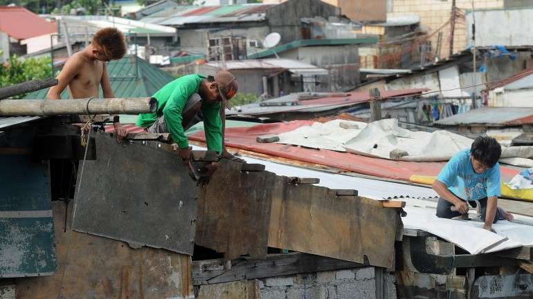 Habitantes de Manila reparam as casas depois da passagem do Tufão Noul