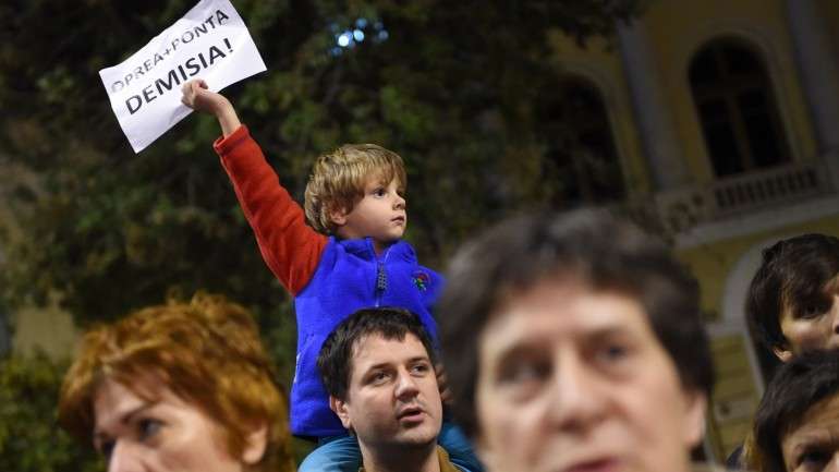 Menino ergue cartaz a pedir a demissão do primeiro-ministro, Victor Ponta, e do ministro do Interior, Gabriel Oprea