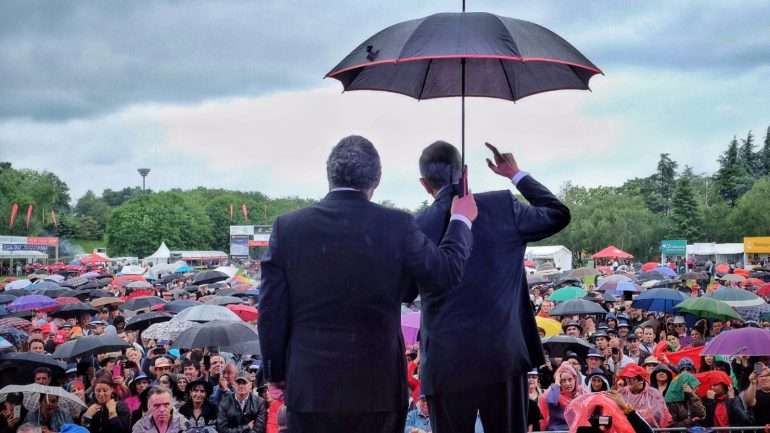 António Costa segura um guarda-chuva para abrigar Marcelo Rebelo de Sousa da Chuva, em Paris
