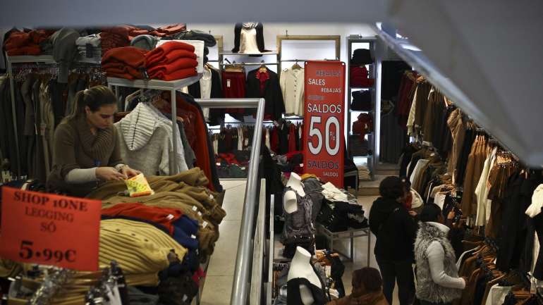 Clientes fazem compras numa loja com produtos em saldos no dia em que se iniciam os saldos de Inverno