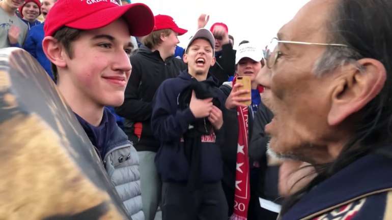 À esquerda, o estudante de um colégio católico com um boné com o slogan  de Trump; à direita, o ativista índio