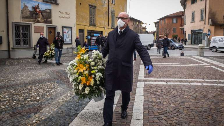 Ao assistir a funerais as pessoas de Bérgamo têm utilizado máscaras