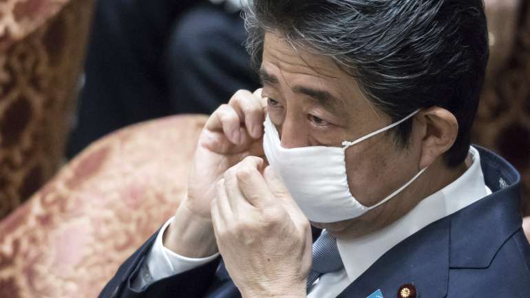 O primeiro-ministro japonês com uma das máscaras reutilizáveis que tem sido distribuída