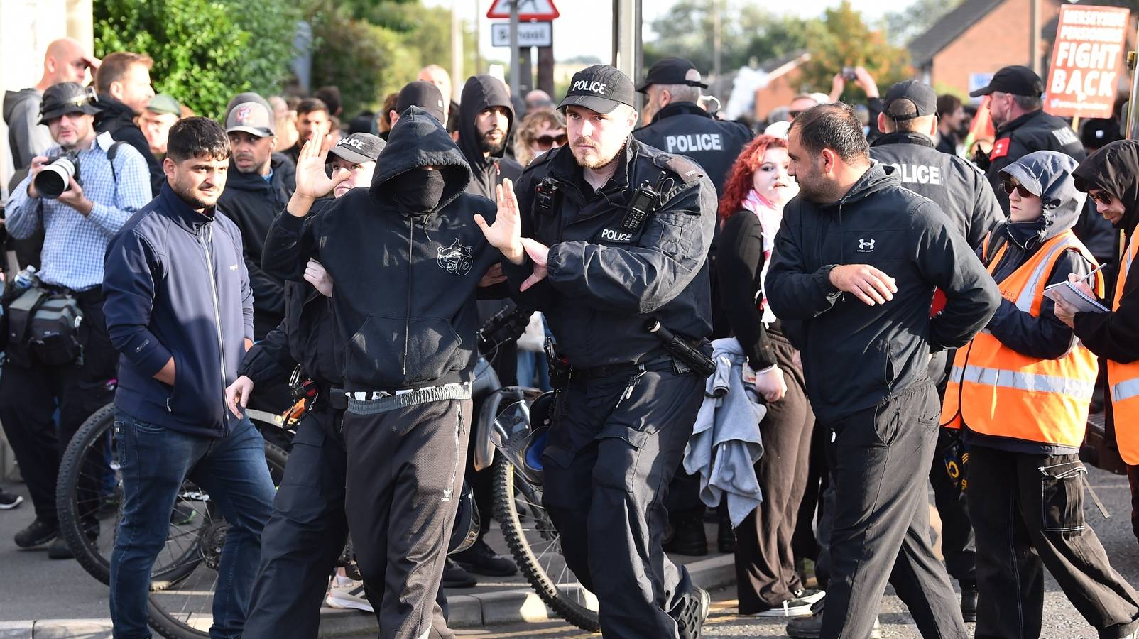 epaselect epa11534599 Police remove a protester who refused to remove their face mask outside the Merseyside Refugee Centre in Liverpool, Britain, 07 August 2024. Further far-right protests are expected throughout Britain on the 07 August 2024. Violent demonstrations have been held by members of far-right groups across Britain following a fatal stabbing attack in Southport, in which three children were killed and eight more seriously injured, along with two adults.  EPA/PETER POWELL