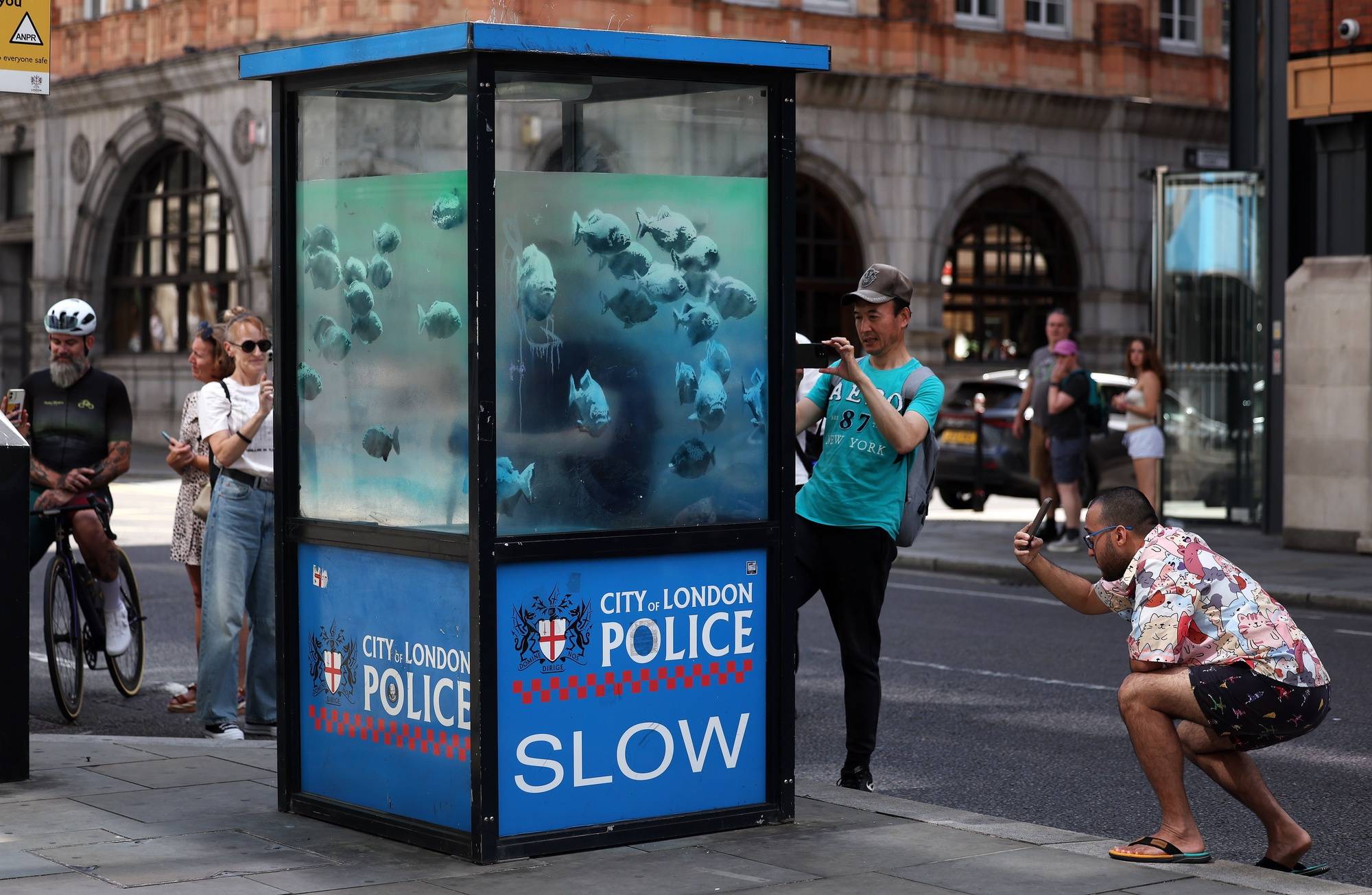 epa11545404 People gather to look at an artwork by Britain-based street artist Banksy on an old police sentry box in the City of London in London, Britain, 11 August 2024. It is the seventh animal artwork claimed by the artist in the past week. Banksy has claimed one art piece a day for seven days, posting a photo at 1pm local time on social media every day.  EPA/ANDY RAIN