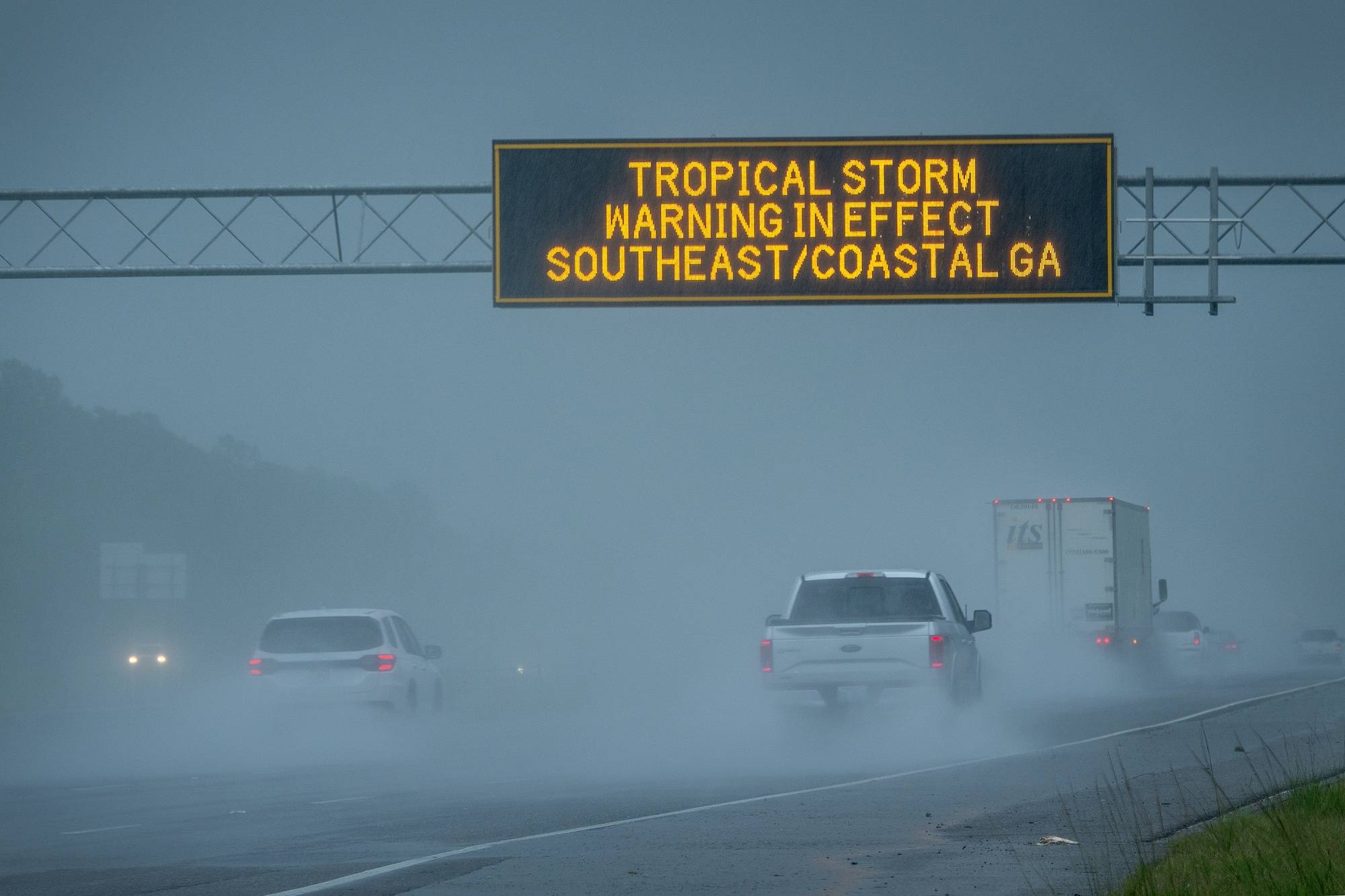 epa11529124 Vehicles pass under a tropical storm warning sign in effect due to tropical storm Debby in Waverly, Georgia, USA, 05 August 2024. Debby made landfall in Florida&#039;s Big Bend as a hurricane and is now a tropical storm that can produce potentially historic heavy rainfall across southeast Georgia, part of South Carolina and southeast North Carolina according to the National Hurricane Center.  EPA/CRISTOBAL HERRERA-ULASHKEVICH