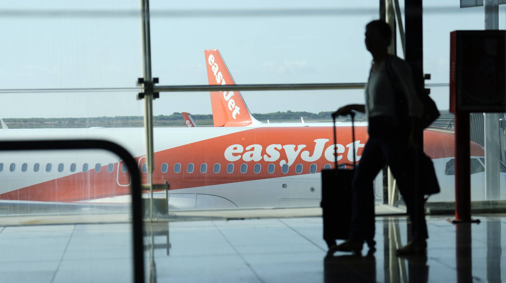 epa10116908 A man walks past an EasyJet plane at El Prat airport, Barcelona, Spain, 12 August 2022. The first day of the EasyJet pilots&#039; strike in August has caused cancellations at El Prat and in Palma de Mallorca Airports.  EPA/ALEJANDRO GARCIA