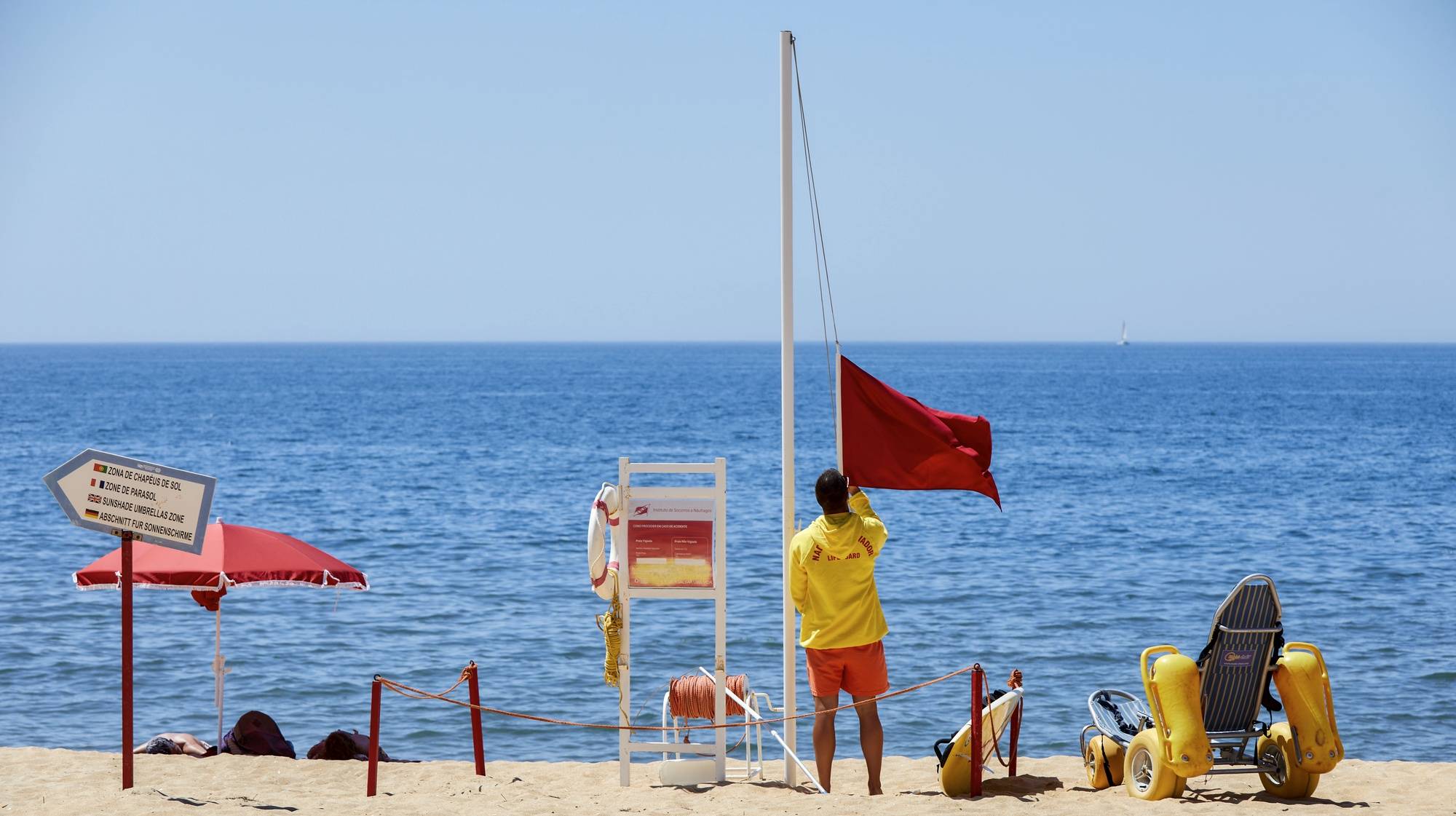 Um nadador-salvador da praia de Quarteira retira a bandeira vermelha, que interditava os turistas a banhos devido à presença de bactérias prejudiciais à saúde na água do mar, para hastear a bandeira verde que permite os banhos, após nova análise à qualidade da água nas praias de Quarteira e Vale do Lobo, em Loulé, 26 de julho de 2023. A interdição a banhos nas praias de Quarteira e Vale do Lobo, no Algarve, que durou menos de 24 horas e cuja interdição foi hoje levantada, foi causada por um foco de poluição. RICARDO NASCIMENTO/LUSA