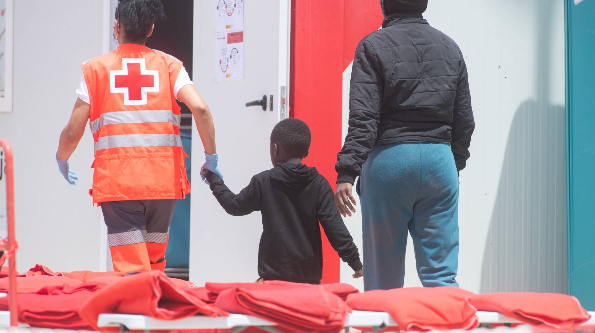 epa11329546 A Red Cross staff assists rescued migrants at the port of Gran Tarajal, slas Canarias, Spain, 09 May 2024. Maritime Rescue has rescued 112 migrants of sub-Saharan origin who were trying to reach Fuerteventura in two inflatable boats, including three women and a child.  EPA/Carlos de Saa