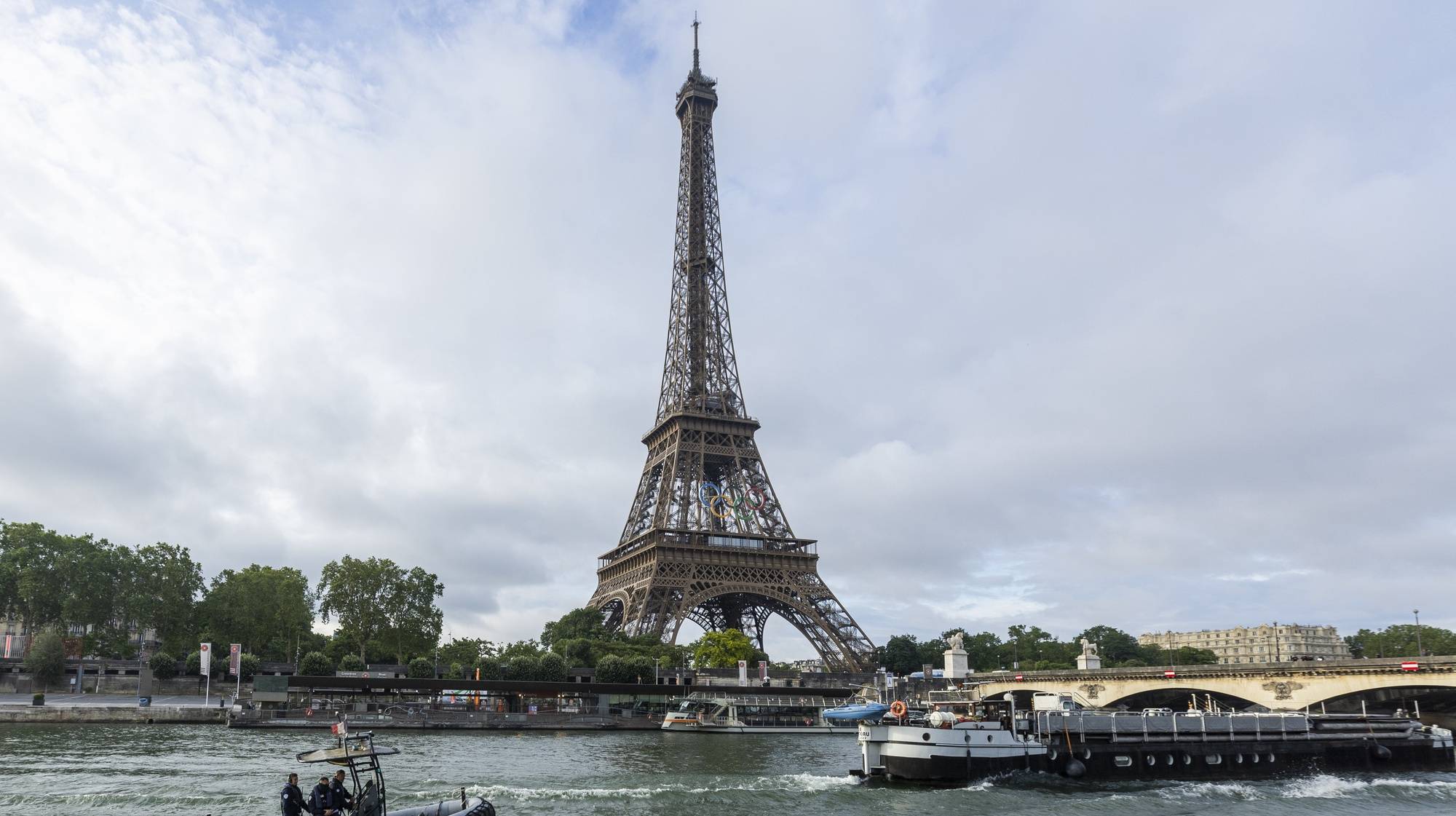 epaselect epa11417308 Sightseeing boats and a police rubber dinghy sail on the Seine river near the landmak Eiffel tower during a rehearsal for the Opening Ceremony of the 2024 Paris Olympic Games, in Paris, France, 17 June 2024. The Olympic Games in the French capital will take place from 26 July to 11 August 2024.  EPA/ANDRE PAIN