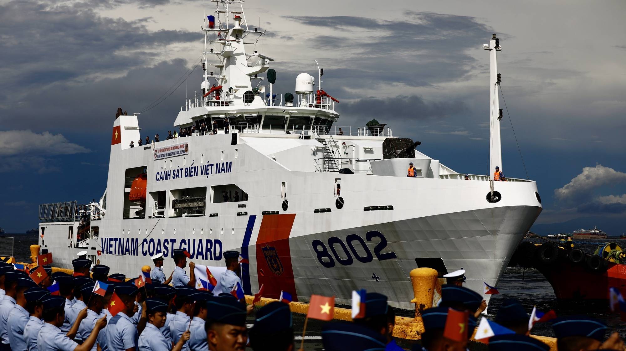 epa11526589 Philippine Coast Guard personnel wave flags as the Vietnam Coast Guard CSB-8002 patrol ship makes a port call at the Port of Manila, Philippines, 05 August 2024. Philippine and Vietnam coastguards will conduct joint maritime exercises in the disputed South China sea to foster mutual understanding and enhanced cooperation between the two nations.  EPA/FRANCIS R. MALASIG