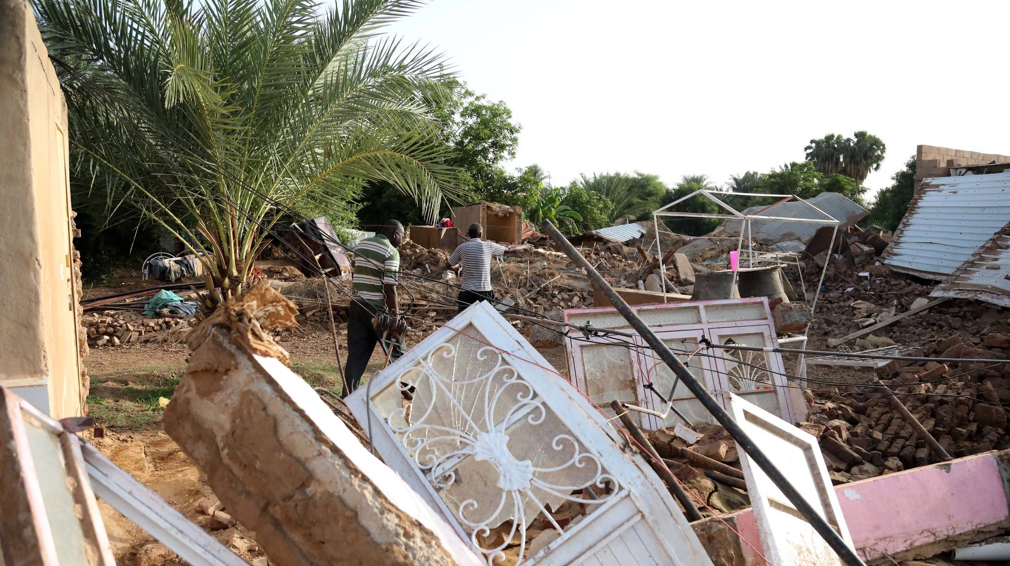 epa07794026 Sudanese walk amid the rubble of houses destroyed following heaving floods, in Geli, some 40 km north of Khartoum, Sudan, 25 August 2019. According to local witnesses, Geli inhabitants were surprised by the sudden and heavy arrival of water in their streets. Heavy rain waters coming from higher grounds around them reached them in the form of a flash flood. Geli dwellers said that some 600 mostly mud houses had been destroyed. According to aid agencies reports, floods have affected some 190,000 people in various states of Sudan, reportedly killing 60.  EPA/MARWAN ALI