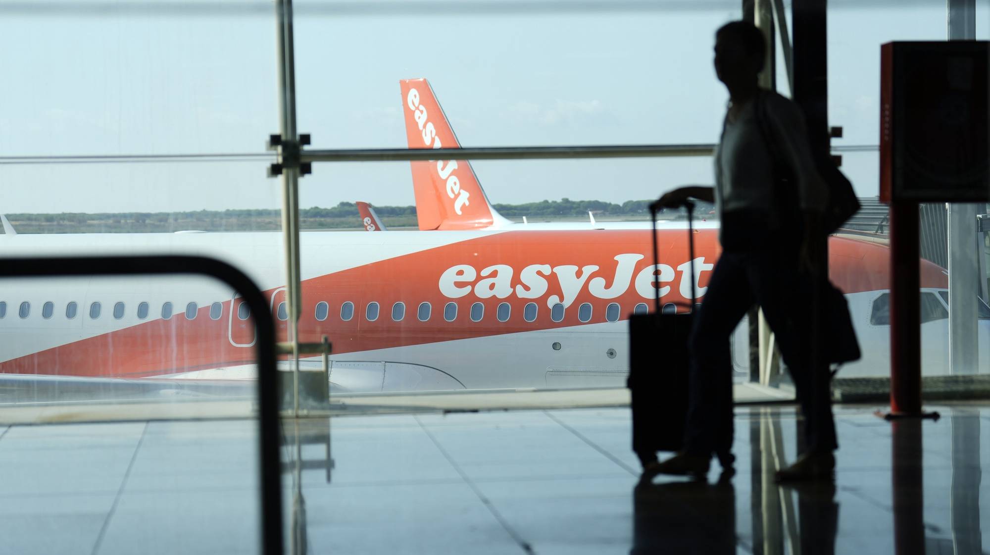 epa10116908 A man walks past an EasyJet plane at El Prat airport, Barcelona, Spain, 12 August 2022. The first day of the EasyJet pilots&#039; strike in August has caused cancellations at El Prat and in Palma de Mallorca Airports.  EPA/ALEJANDRO GARCIA