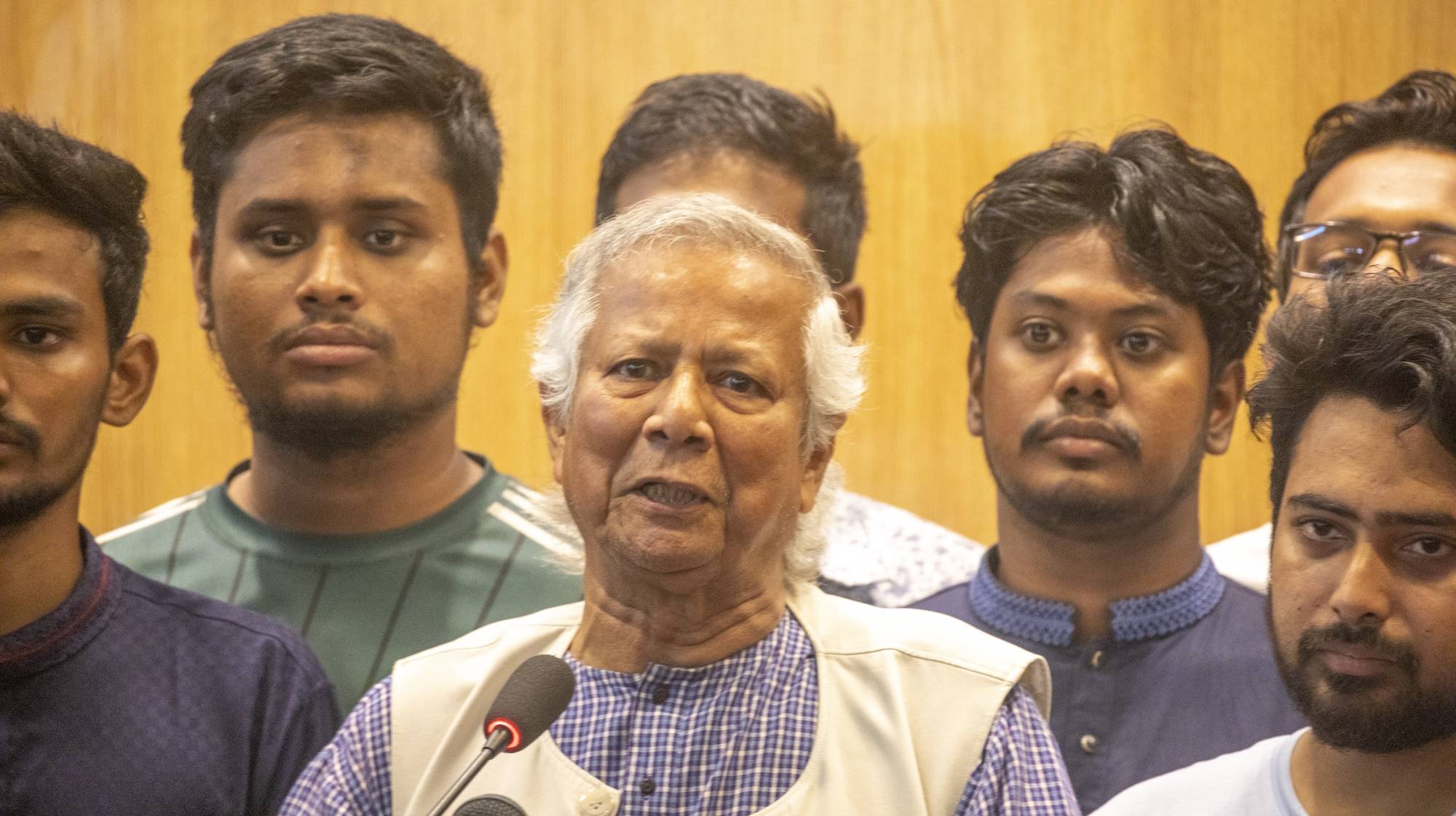 epa11537708 Nobel laureate Muhammad Yunus (C), surrounded by quota protests student leaders, speaks to the media after arriving in Dhaka at Hazrat Shahjalal International Airport, in Dhaka, Bangladesh, 08 August 2024. Yunus was sworn in as the head of Bangladesh&#039;s interim government on 08 August after former prime minister Sheikh Hasina had resigned and fled the country amid violent protests over the government&#039;s job quota system.  EPA/MONIRUL ALAM