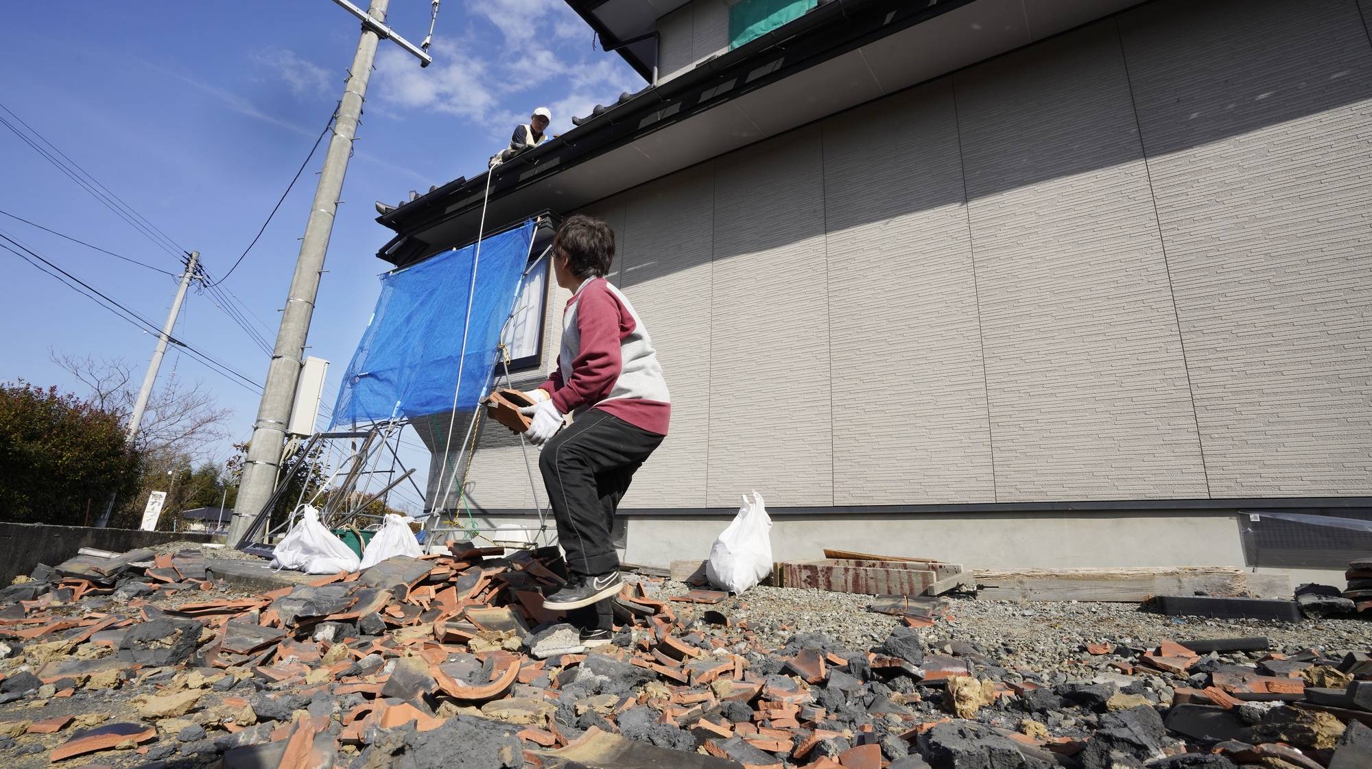 epa09011268 Residents collect damaged roof tiles after a powerful magnitude 7.3 earthquake in Soma, Fukushima Prefecture, northern Japan, 14 February 2021. A powerful earthquake hit northern Japan around midnight on 13 February 2021. More than 120 people have been reported injured in the quake. The Tokyo Electric Power Company (TEPCO) has reported no damages at its Fukushima Daiichi Nuclear Power Plant and Fukushima Daini Nuclear Power Plant. More than 900,000 homes suffered from a power outage, which has been almost restored, according to TEPCO and Tohoku Electric Power.  EPA/KIMIMASA MAYAMA