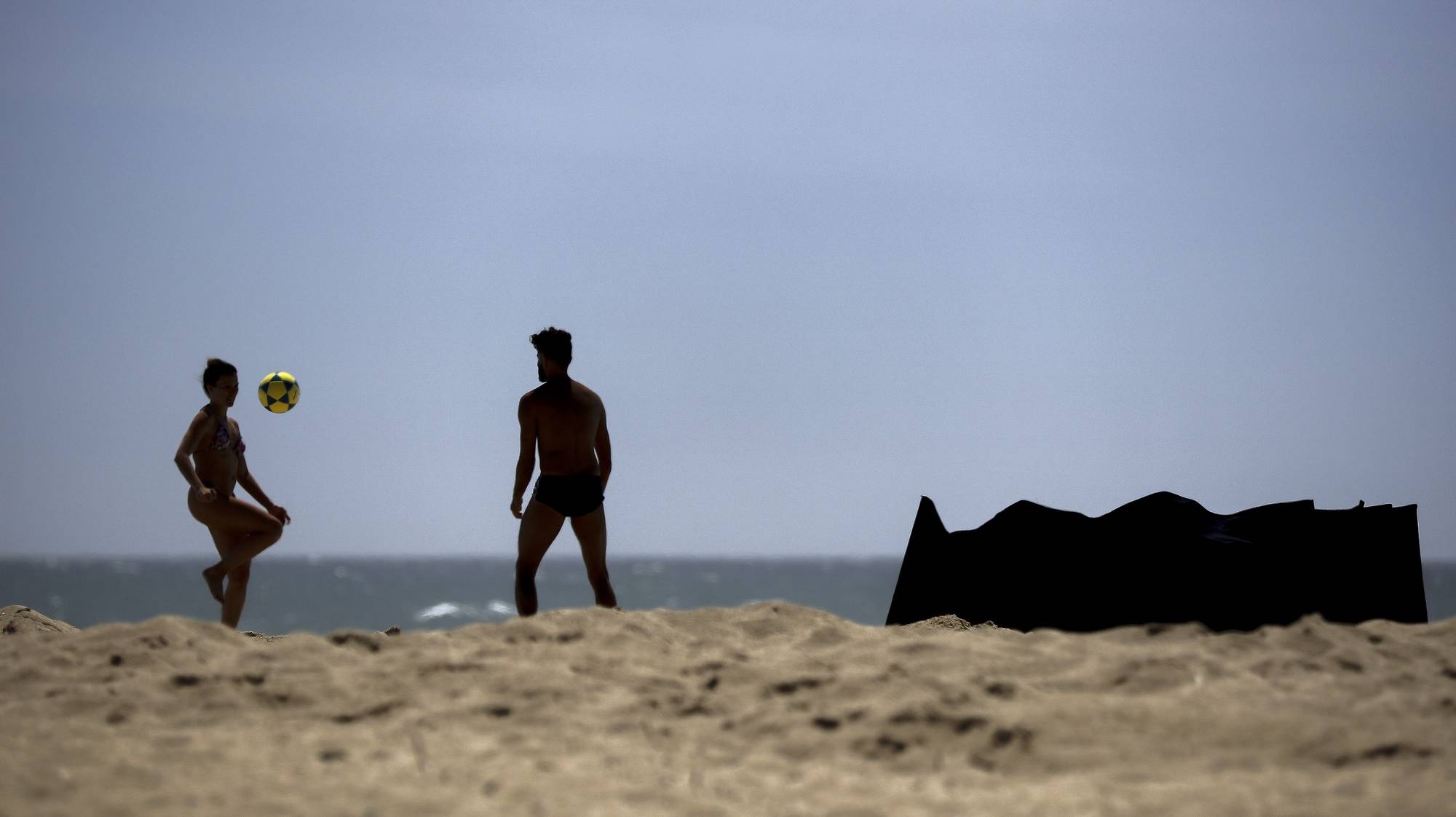 Banhistas jogam à bola à beira-mar na praia da Póvoa de Varzim, 23 de maio de 2020. Apesar de o Governo ter marcado a abertura do período balnear para 6 de junho, pode ir-se à praia, após a resolução do Conselho de Ministros que prorroga a declaração da situação de calamidade, no âmbito da pandemia da doença covid-19, datada de dia 17 de maio. MANUEL FERNANDO ARAÚJO/LUSA