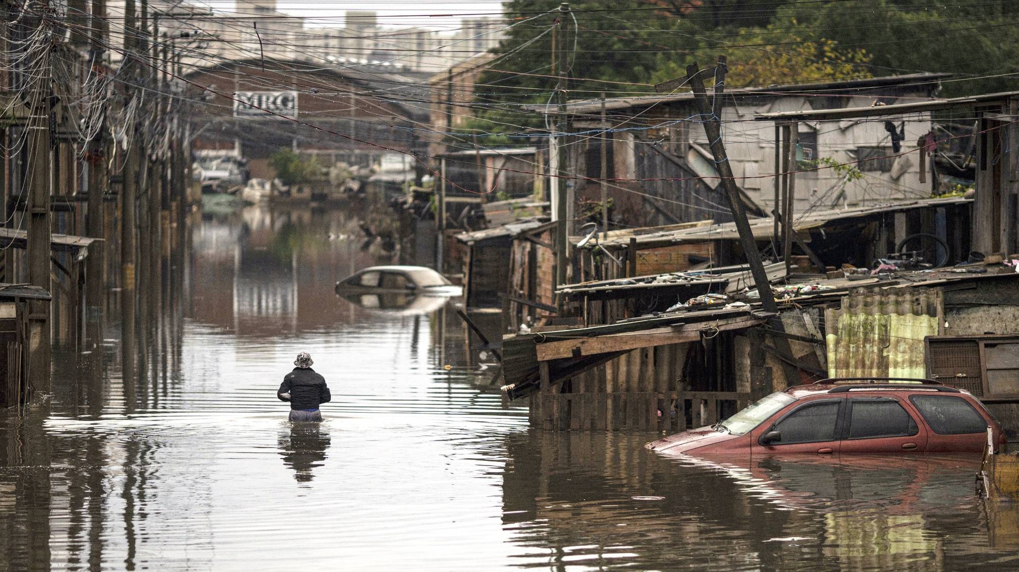 epa11364736 A woman walks in the middle of a flood affected area in the city of Porto Alegre, in Rio Grande do Sul, Brazil, 23 May 2024. Residents in southern Brazil began cleaning their homes in cities and neighborhoods where river levels have dropped, almost three weeks after the onset of unprecedented flooding. In Porto Alegre, the capital of the state of Rio Grande do Sul, the Guaiba River dropped to 3.90 meters still 90 centimeters above flood level, but a significant reduction from the record 5.35 meters reached in early May.  EPA/Daniel Marenco