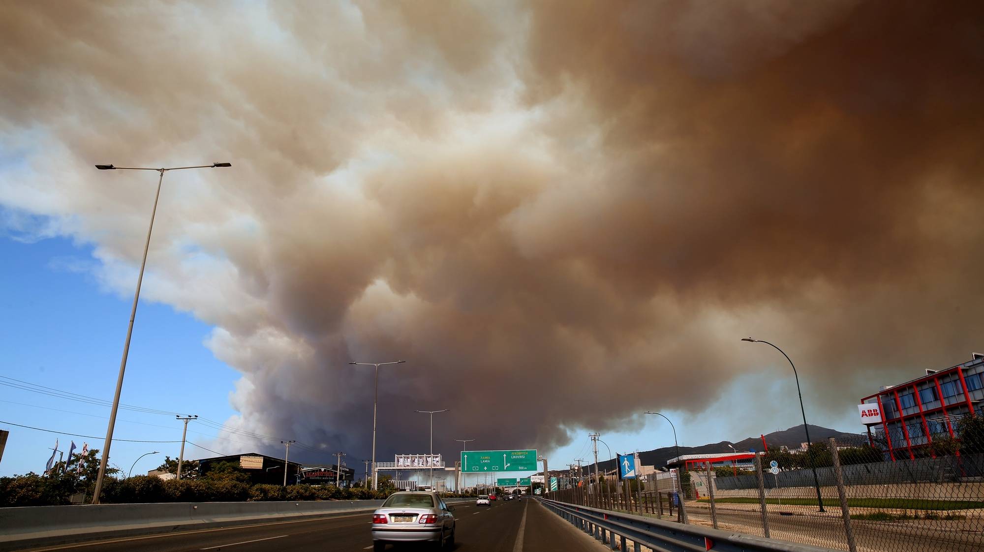 epa11545603 Thick smoke covers the National Highway in Athens from a wildfire that broke out in a farmland and forest area in Varnavas, Attica region, Greece, 11 August 2024. The fire brigade has deployed 165 firefighters, nine teams on foot, 30 vehicles, seven firefighting aircraft, and five helicopters to extinguish the flames. Varnavas residents have been instructed to evacuate the area via a message from the 112 emergency number.  EPA/ALEXANDROS BELTES