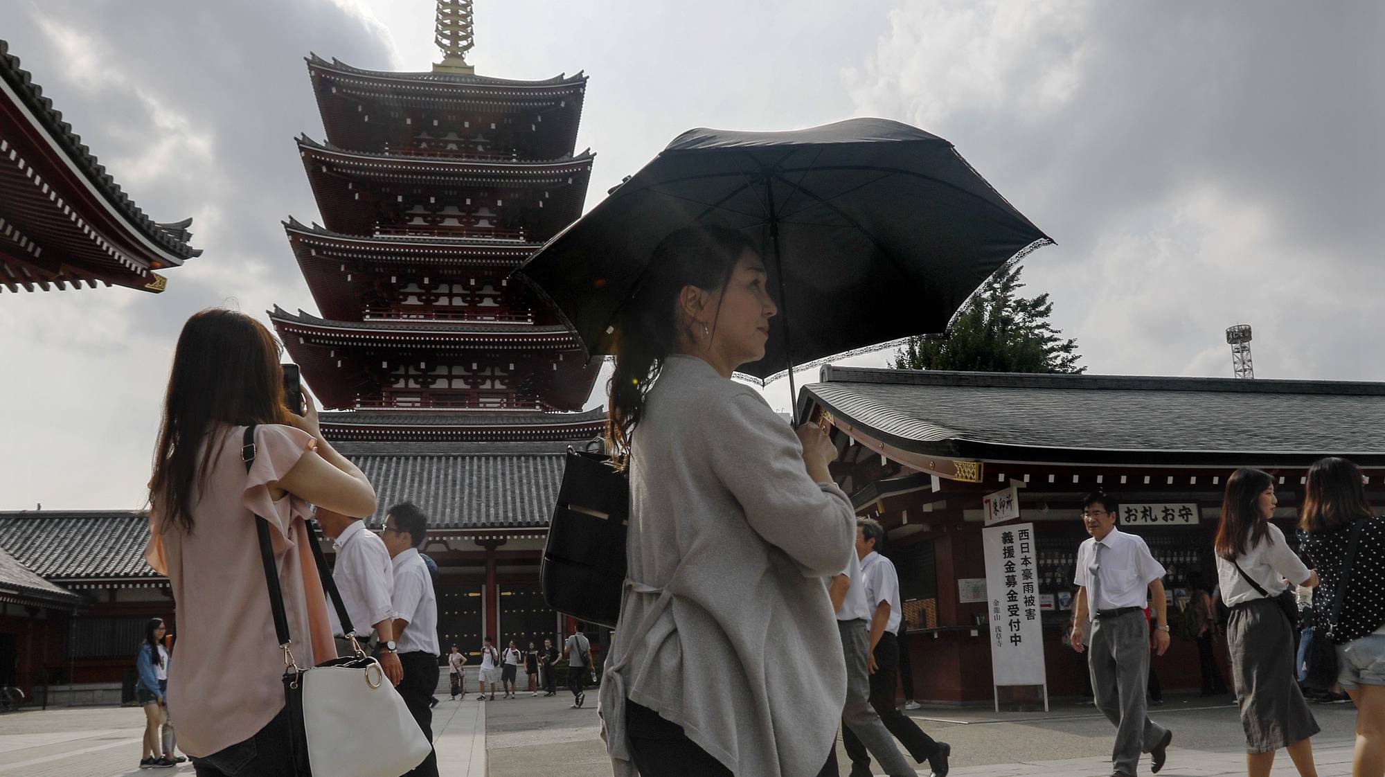 epa06909239 A woman uses her parasol as she walks past the five-story pagoda at the Sensoji temple in downtown Tokyo, Japan, 25 July 2018. In central Tokyo, the temperature rose to 32.2 degrees Celsius, 3.2 degrees lower than the previous day, and Yamaguchi City marked 38.8 degrees Celsius. Typhoon Jongdari, currently in the Pacific Ocean, is moving northward and reducing the heatwave affecting Japan and will possibly make direct landfall on Tokyo and Japan&#039;s main island of Honshu on the weekend.  EPA/KIMIMASA MAYAMA