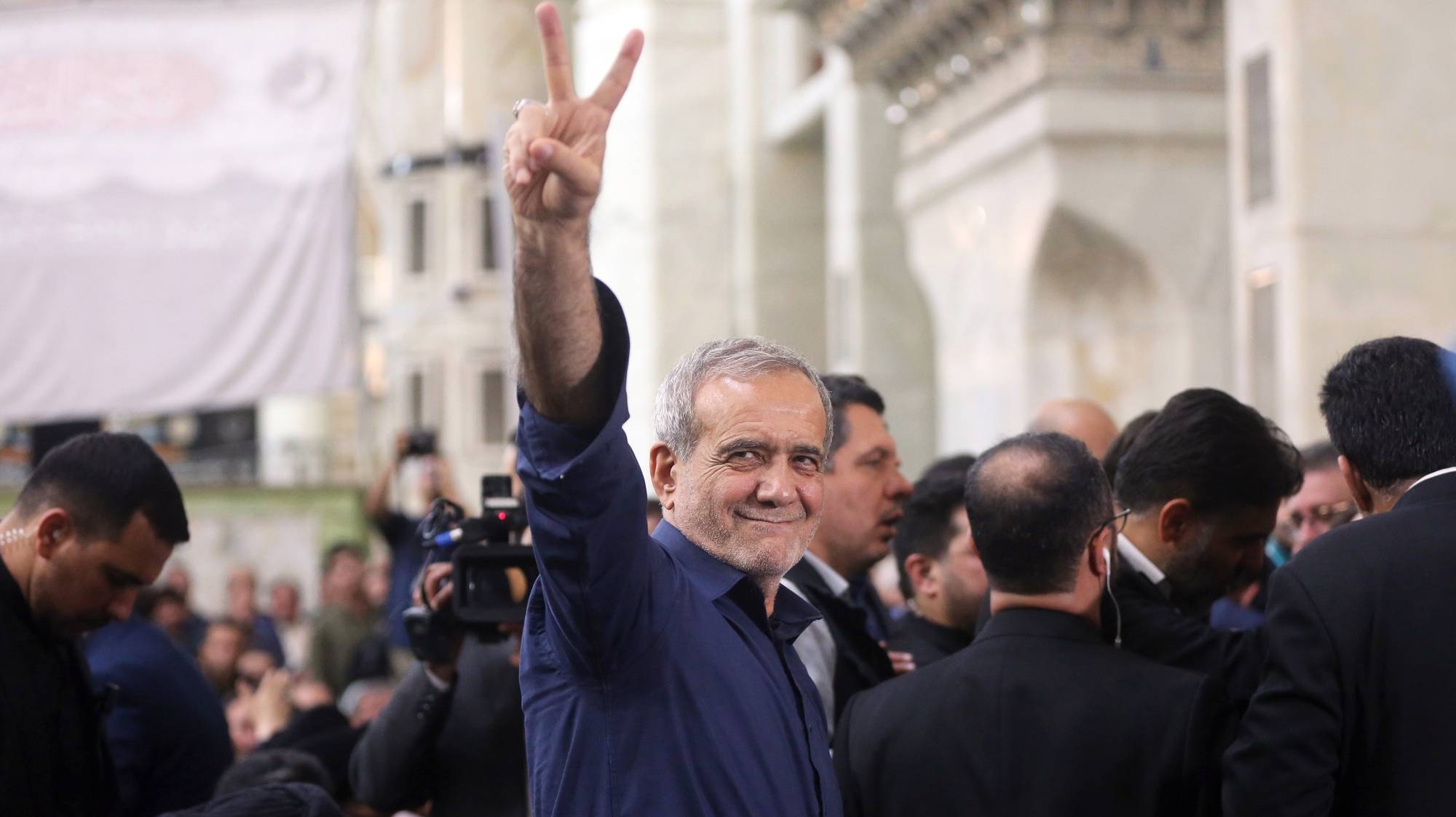 epa11463085 Iranian elected president Masoud Pezeshkian (C) flashes a victory sign to the crowd after winning the presidential elections, at the Khomeini shrine in southern Tehran, Iran, 06 July 2024.  EPA/STR