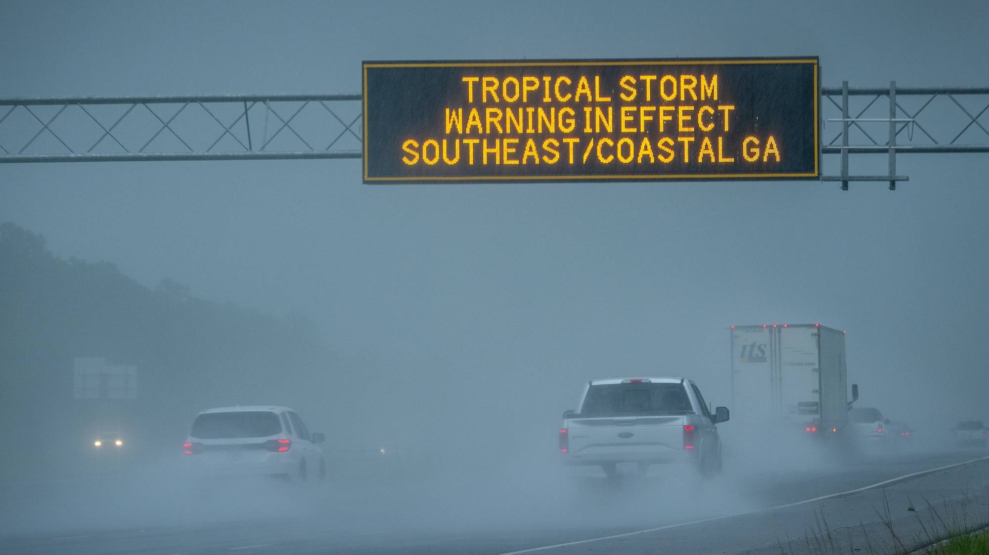 epa11529124 Vehicles pass under a tropical storm warning sign in effect due to tropical storm Debby in Waverly, Georgia, USA, 05 August 2024. Debby made landfall in Florida&#039;s Big Bend as a hurricane and is now a tropical storm that can produce potentially historic heavy rainfall across southeast Georgia, part of South Carolina and southeast North Carolina according to the National Hurricane Center.  EPA/CRISTOBAL HERRERA-ULASHKEVICH