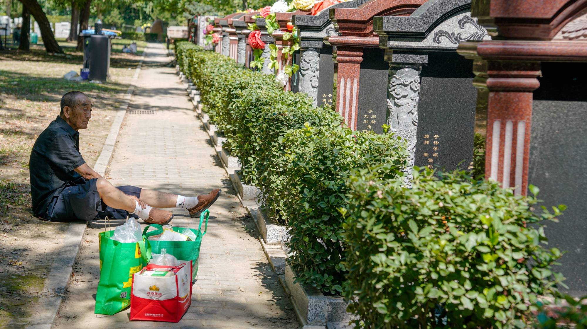 epa10828047 An elderly man sits beside tombs at a cemetery in Beijing, China, 30 August 2023. The Hungry Ghost Festival, also known as the Zhongyuan Festival, is a traditional Taoist and Buddhist festival held in certain East Asian countries. According to the Chinese calendar, the Ghost Festival is on the 15th of the seventh month, in which living descendants pay homage to their deceased ancestors.  EPA/WU HAO