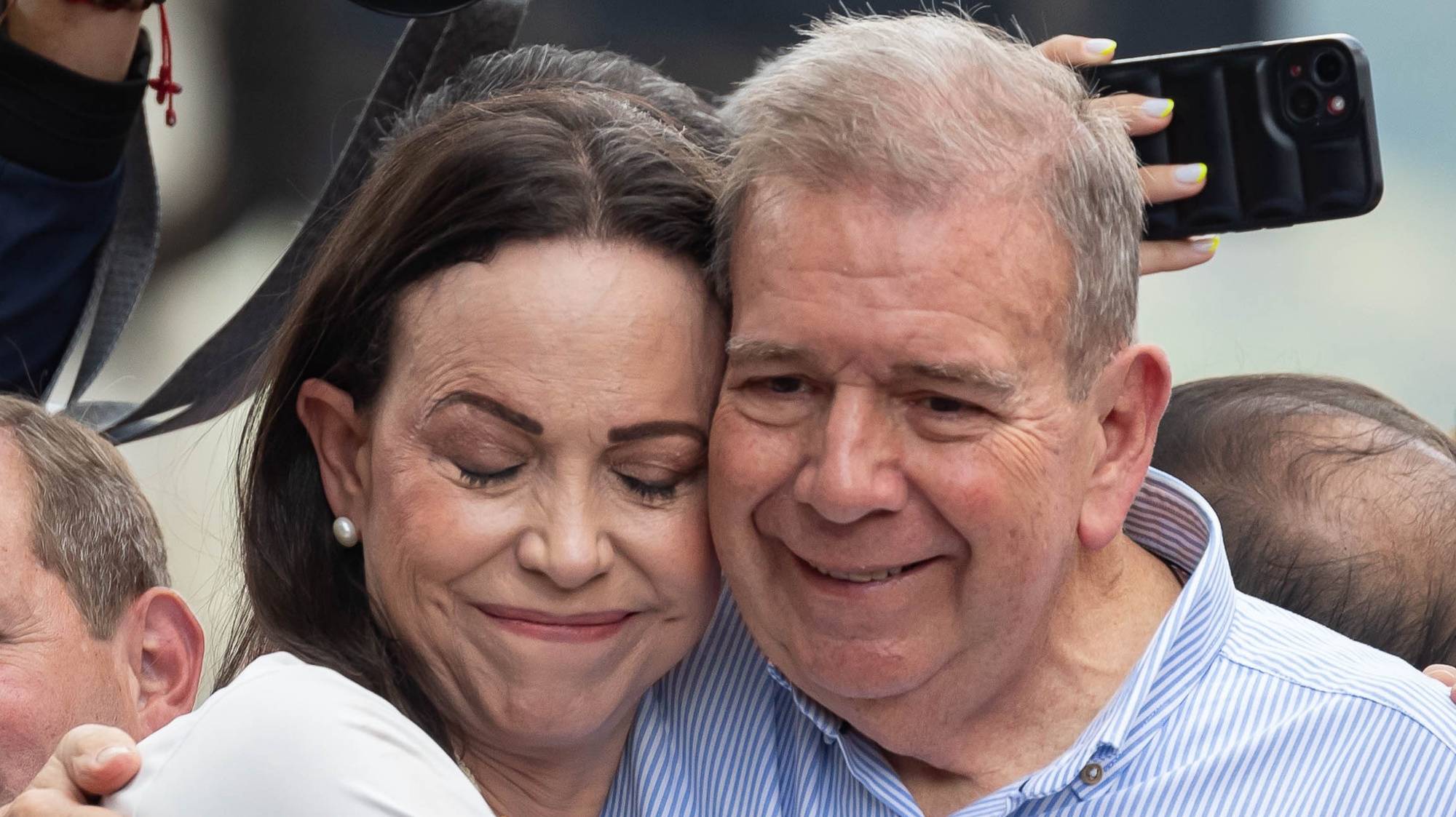 epaselect epa11510252 Venezuelan opposition leader Maria Corina Machado (L) hugs Venezuelan presidential candidate Edmundo Gonzalez Urrutia at a rally in Caracas, Venezuela, 30 July 2024. Thousands of Venezuelans gathered in Caracas on 30 July in an event called by the majority opposition, to reject for the second consecutive day what they consider to be fraud in the official results of the National Electoral Council (CNE), which proclaimed Nicolas Maduro as re-elected president with 51.2 percent of the votes.  EPA/RONALD PENA R