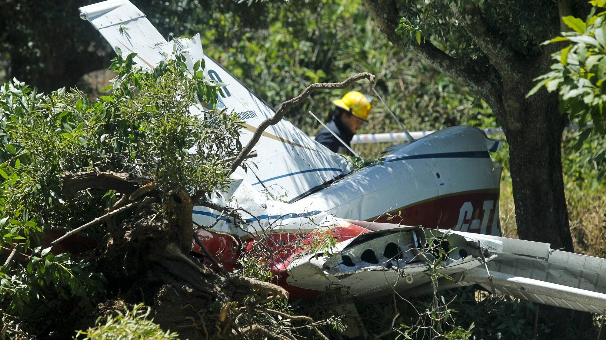 Um elemento dos bombeiros passa junto dos destroços de uma avioneta que se despenhou esta tarde junto ao aerodromo de Tires, provocando dois feridos graves, em Tires, 03 de julho de 2012. MIGUEL A. LOPES / LUSA