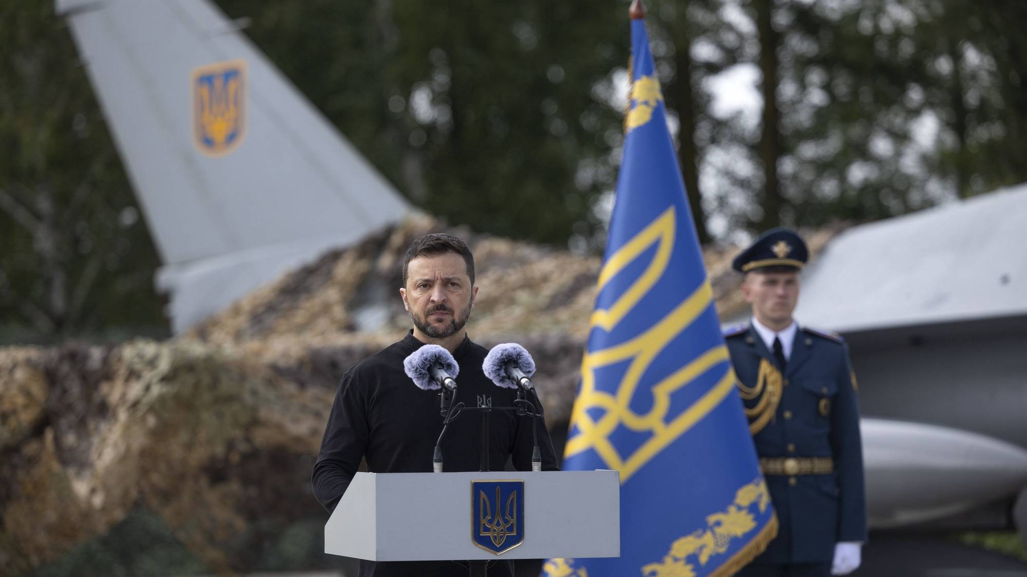 epa11525678 A handout picture made available by the Presidential Press Service shows Ukrainian President Volodymyr Zelensky speaking to servicemen next to an American single-engine supersonic multirole fighter F-16 jet during a ceremony to mark Air Force Day of the Armed Forces of Ukraine at an undisclosed location in Ukraine, 04 August 2024, amid the Russian invasion. Zelensky emphasized that the number of F-16 aircraft and trained pilots is still insufficient, as the country waits for additional fighters from partner countries.  EPA/PRESIDENTIAL PRESS SERVICE HANDOUT  HANDOUT EDITORIAL USE ONLY/NO SALES